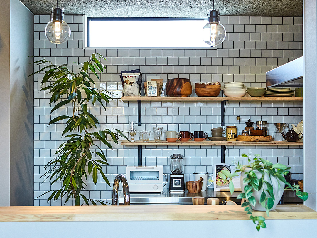 白いタイルに緑の植物が映える清潔感のあるキッチン
